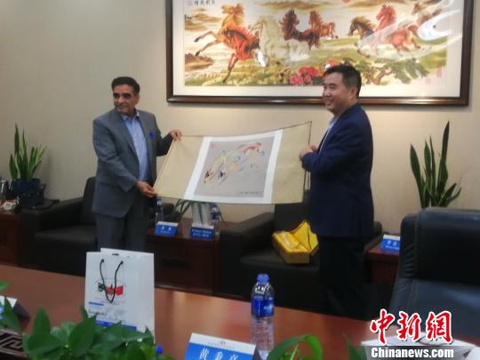 新疆友联会常务副会长胡爱军(右)向巴基斯坦《每日邮报》主编马克东·巴伯(左)赠与纪念品。　古丽米娜 摄